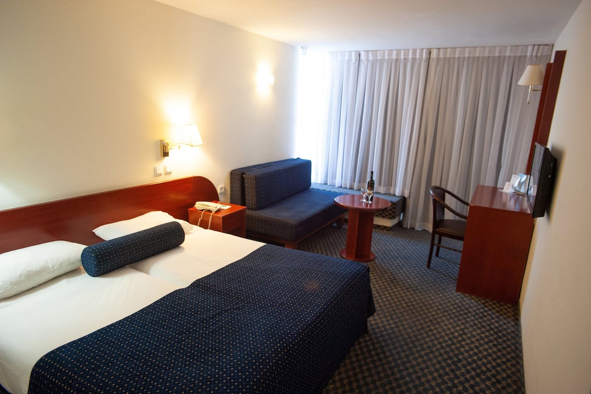 Una habitación de hotel con una cama grande, un sofá, una mesita y una silla.