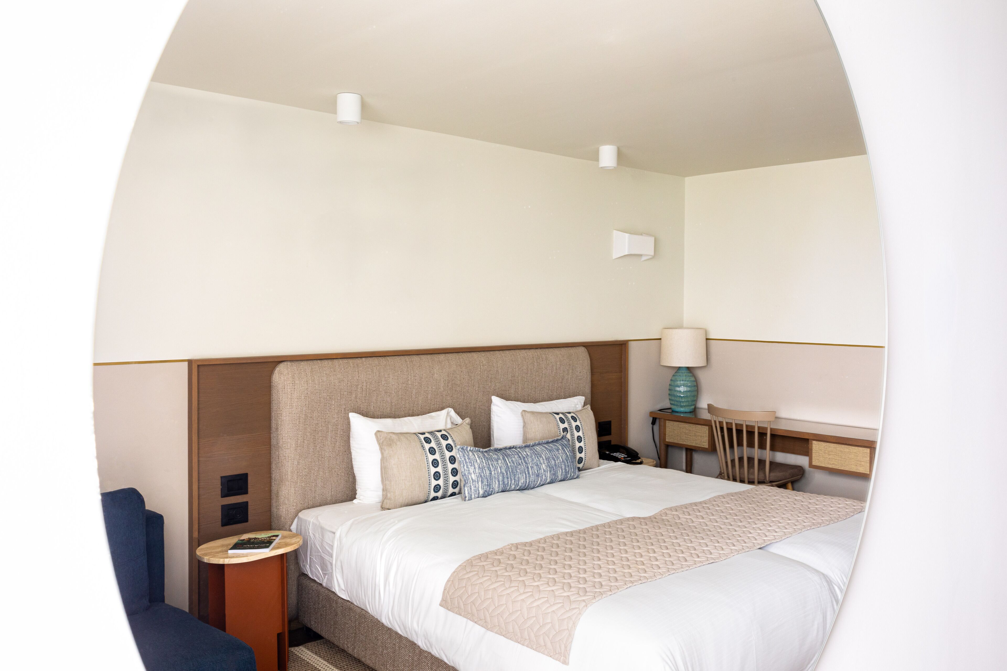 Ein ordentlich eingerichtetes Hotelzimmer mit einem großen Bett, Nachttischen, einem Sessel und einem Schreibtisch.