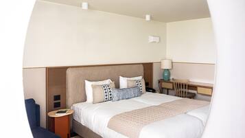 Een verzorgde hotelkamer met een groot bed, nachtkastjes, een stoel en een bureau.