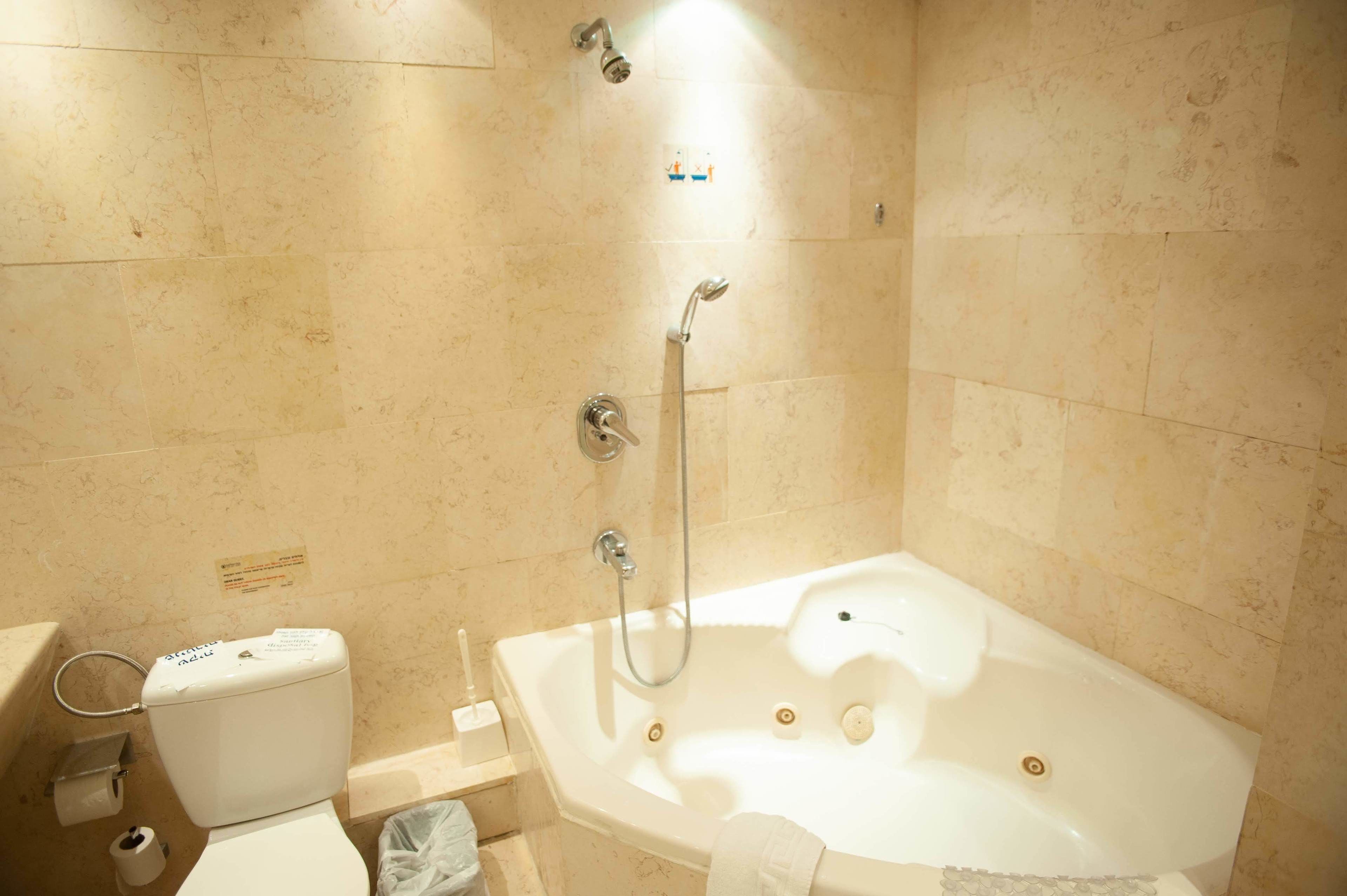 Een badkamer met een bad, toilet en douche.