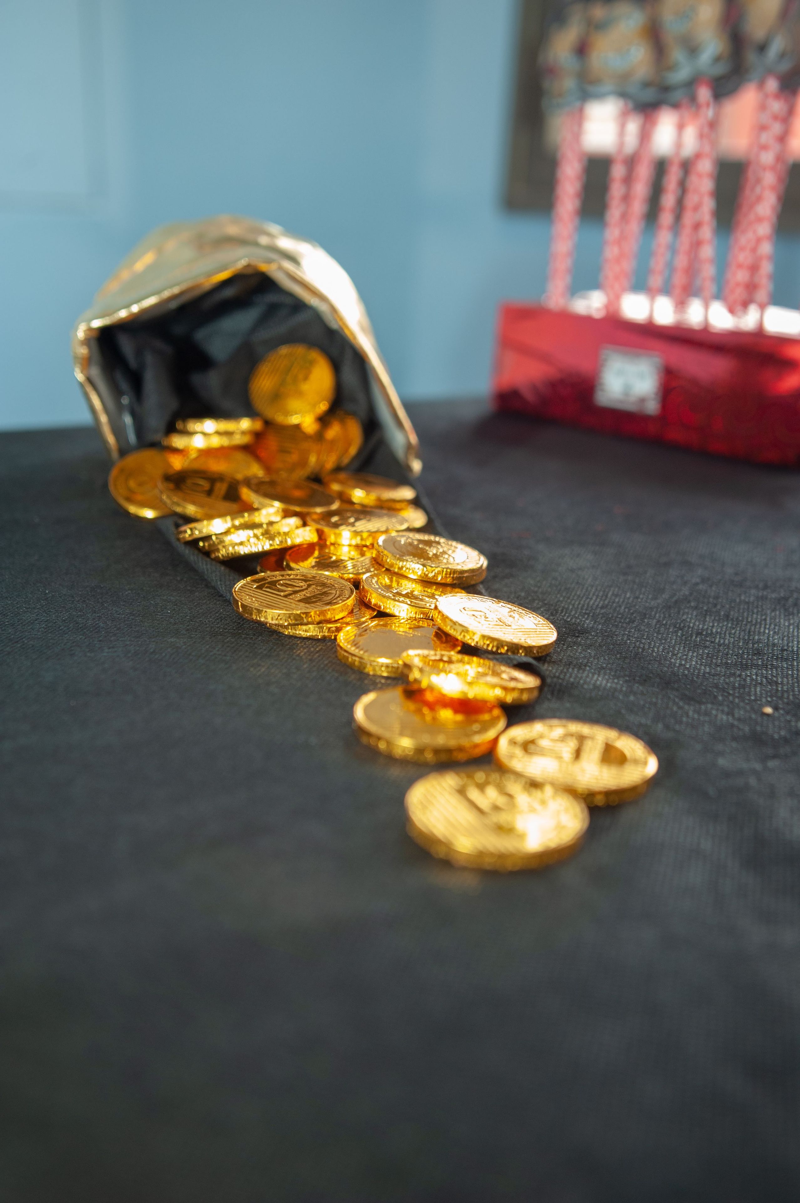 Monedas de oro desbordándose de una bolsa sobre una superficie oscura.