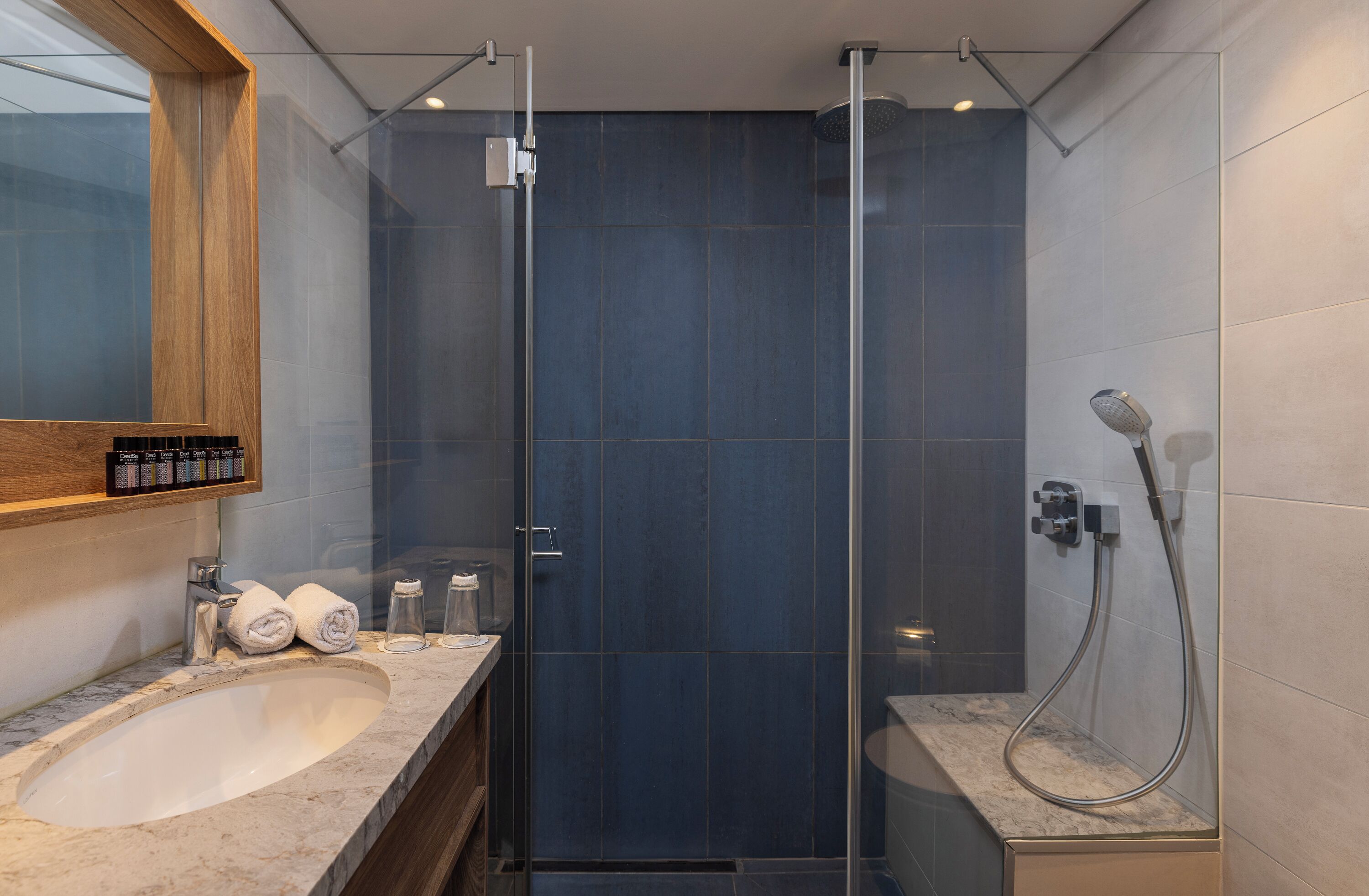 Ein modernes Badezimmer mit einer gläsernen Duschkabine, einem мраморном Waschbecken und einem hölzernen Medikamentenschrank.