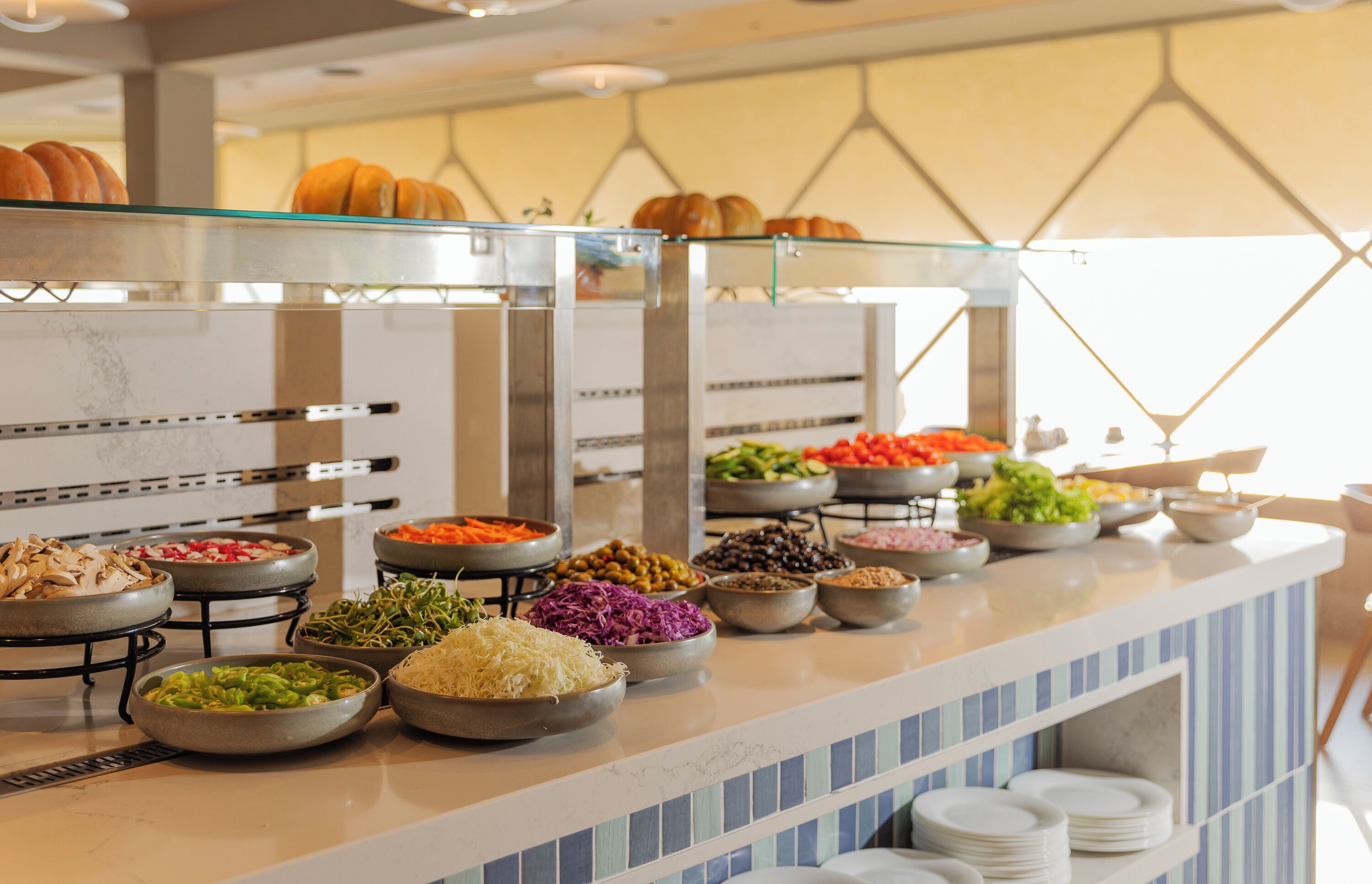 A buffet with various food items and a glass display case with pastries.