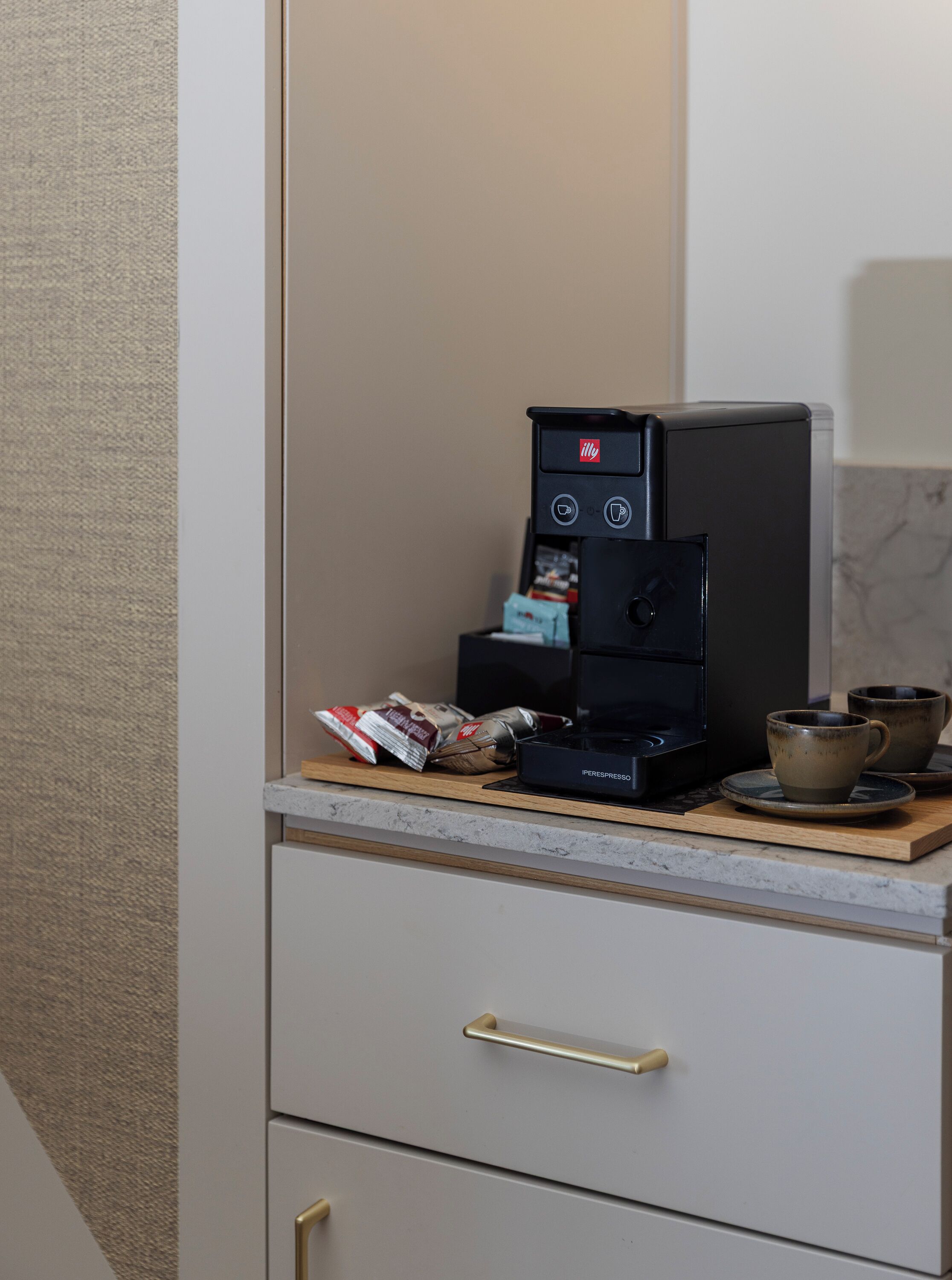 A kitchen with a coffee machine, a coffee cup, and a box of coffee pods on the counter.