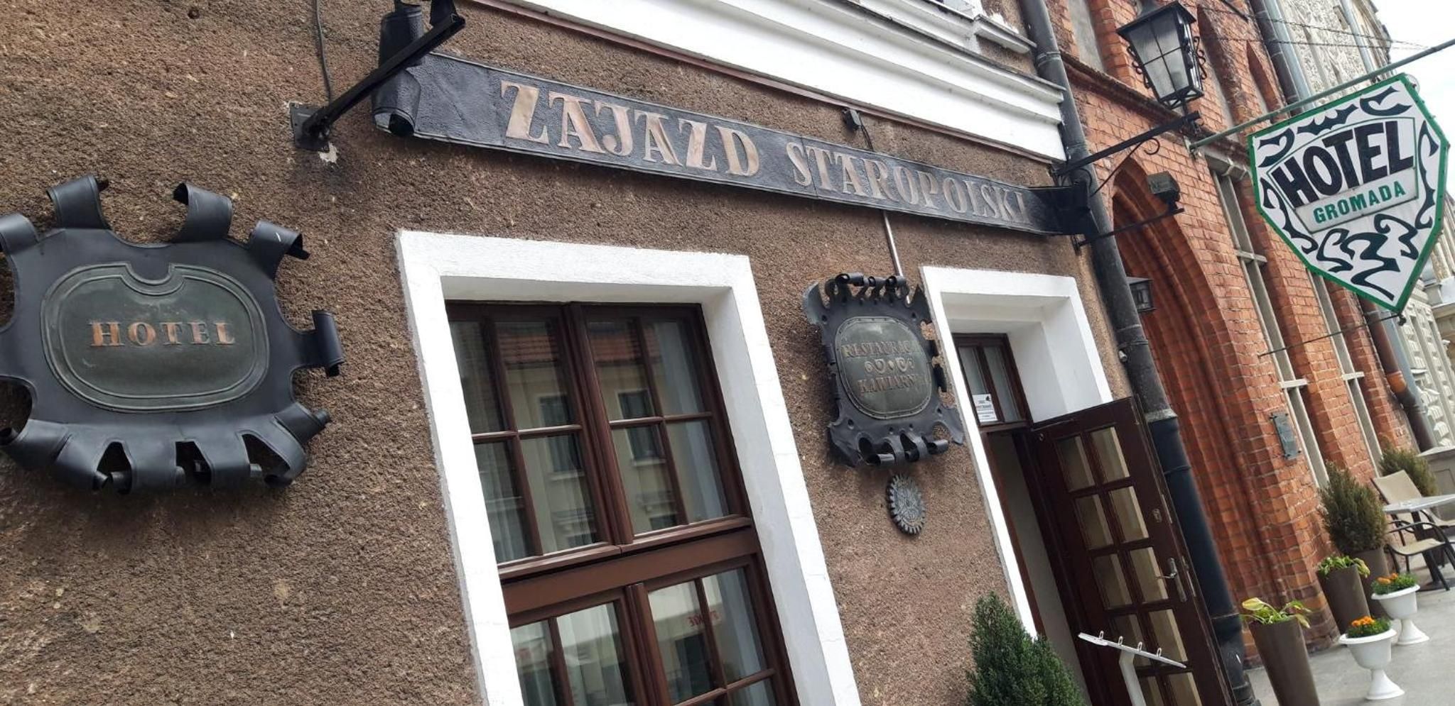 Ein Gebäude mit einem Schild, auf dem 'ZAJAZD STAPOYSKI HOTEL' steht, und einem kleineren Schild mit der Aufschrift 'HOTEL GROMADA'.