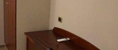 Una habitación con un escritorio de madera, una silla, un televisor montado en la pared y una puerta.