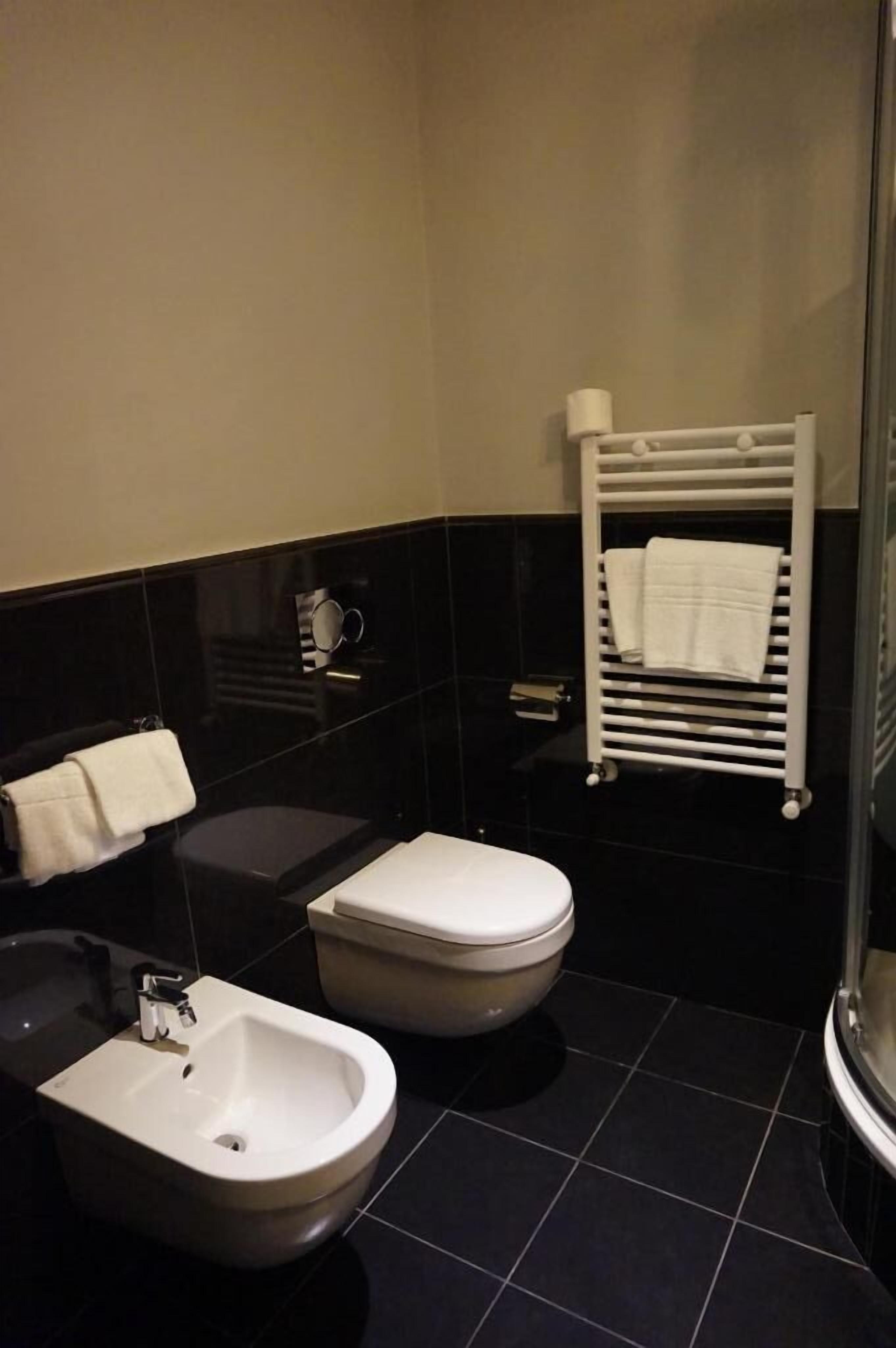 A modern bathroom with a bidet, toilet, and towel rack.