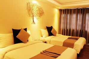 Habitació d'hotel amb dos llits, cada un amb una manta marró, roba de llit blanca i almoines negres. Es veu una decoració d'arbre penjada a la paret sobre els llits.