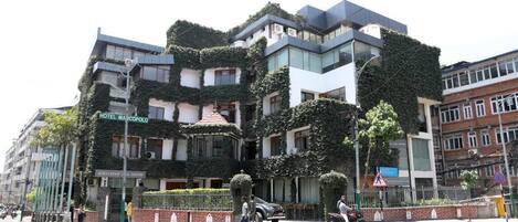 Un edificio moderno con un diseño arquitectónico único, que combina vidrio y vegetación.