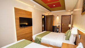 A hotel room with two beds, a TV mounted on the wall, a wardrobe, and a desk with a lamp. - Hotel Marcopolo Pvt Ltd (Kathmandu)
