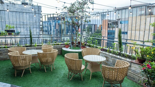 Un patio al aire libre con mobiliario de mimbre, una pequeña mesa redonda y plantas en macetas.
