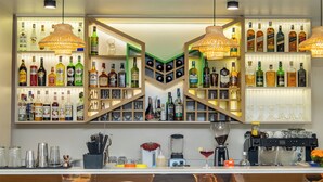 Zona de bar con estanterías llenas de botellas de licores, una máquina de café y utensilios de bar.