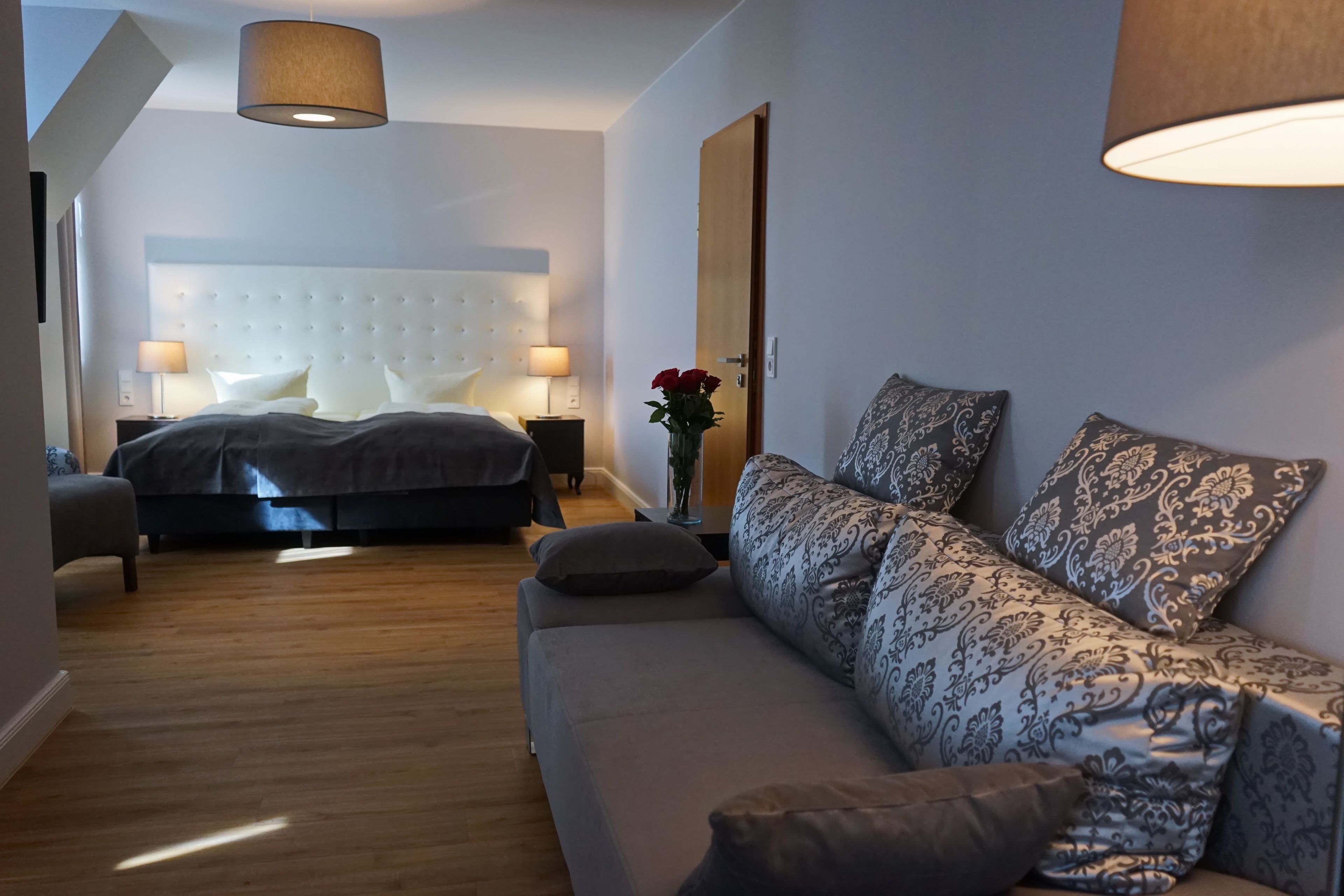 Un dormitorio moderno con una cama grande, un sofá y una mesita de noche con lámparas.