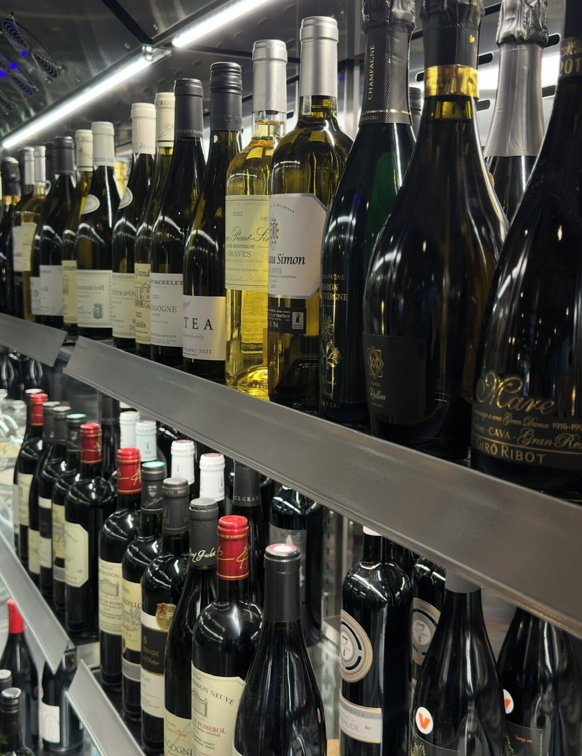 A variety of wine bottles on a shelf in a well-lit area.