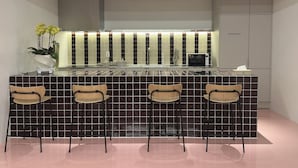 A modern kitchen with a central island, bar stools, a refrigerator, and a potted plant. - Hotel Tradiup by the Designers (Seoul)