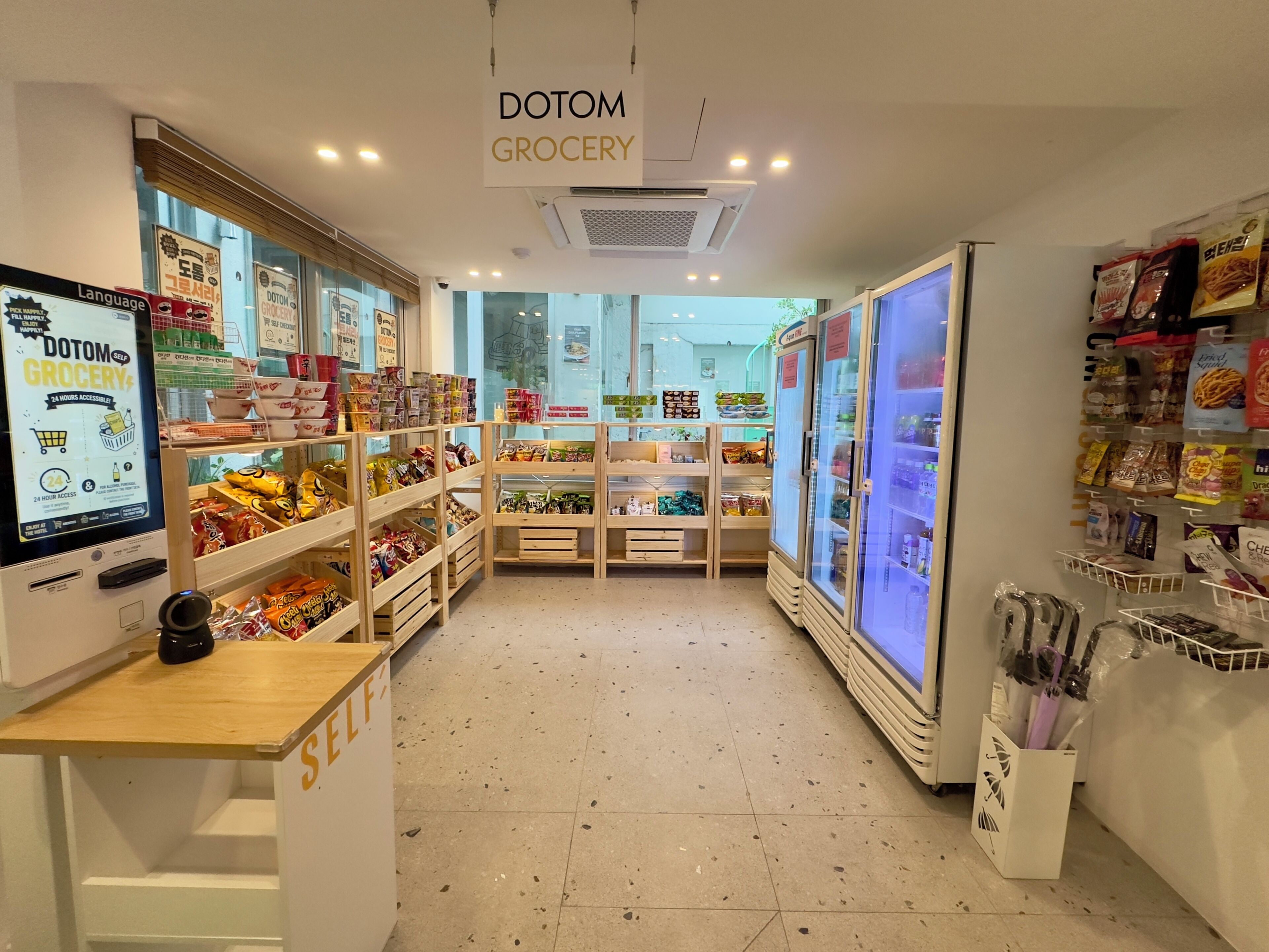 A grocery store interior with self-checkout, refrigerated sections, and shelves stocked with snacks.