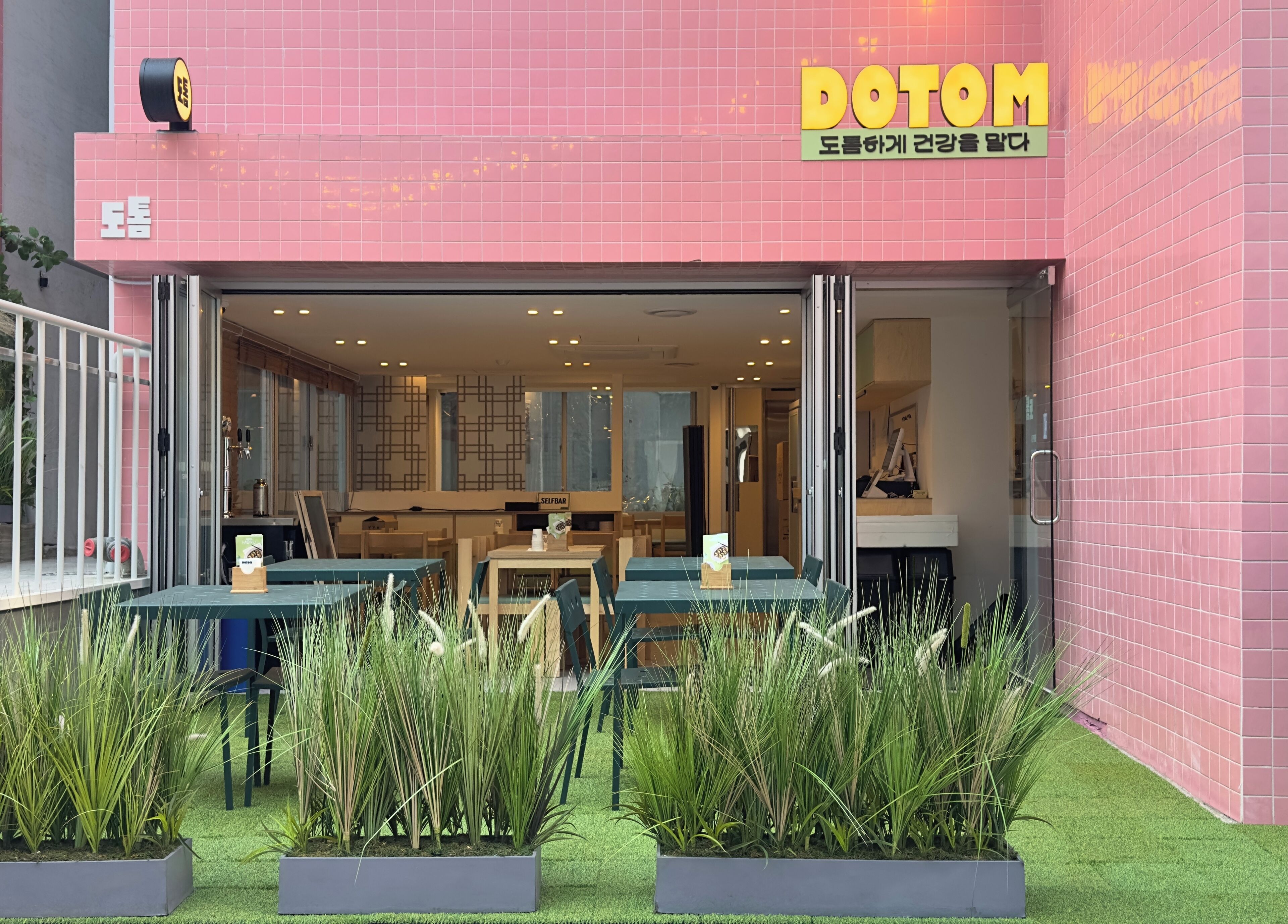 A pink building with a sign reading 'DOTOM' and a self-service bar.