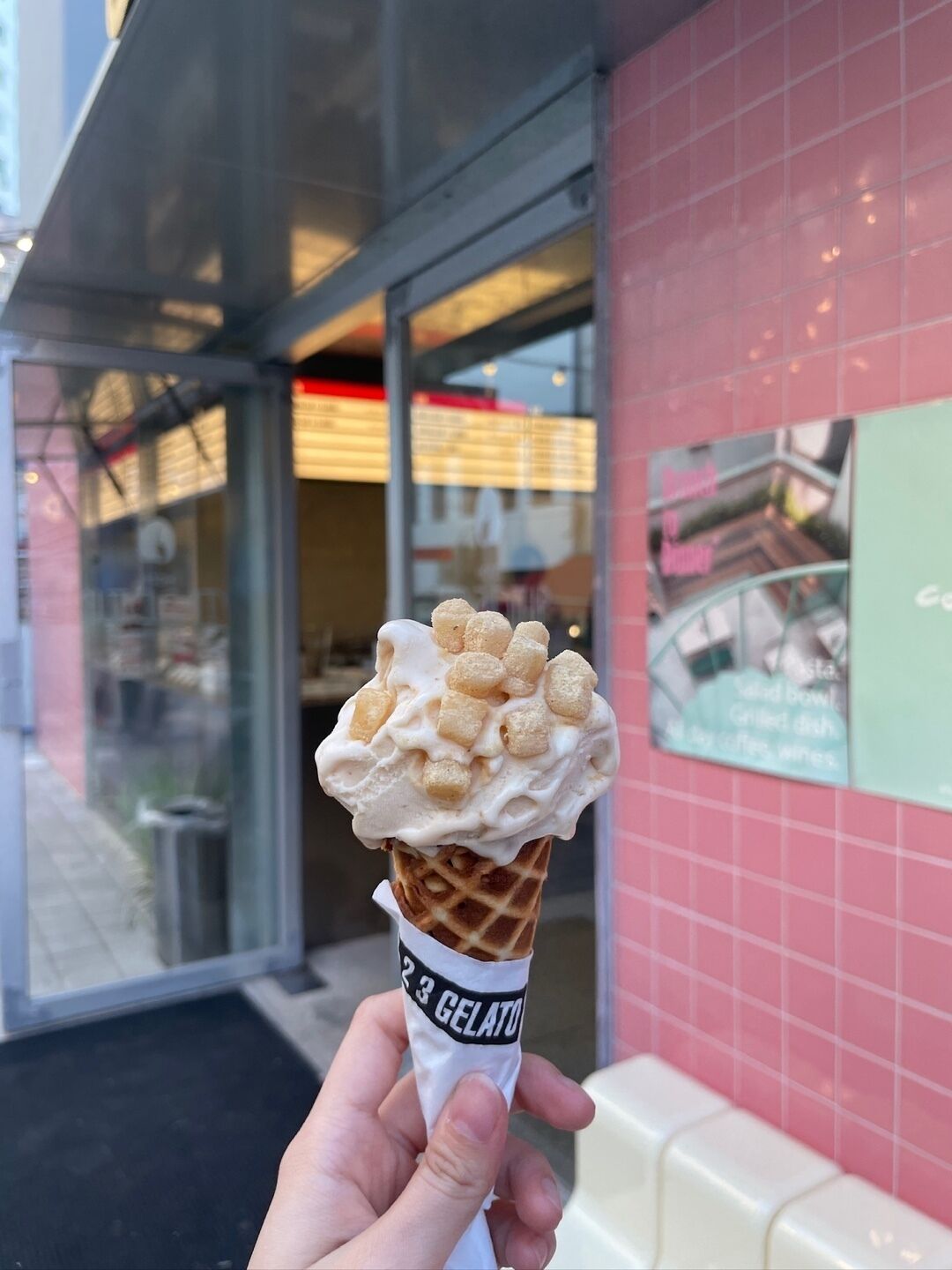Eine Hand hält einen Waffelkorb mit einer Kugel Eis und Marshmallows.