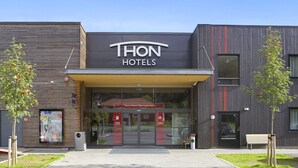 A modern hotel with a prominent 'THON HOTELS' sign, a glass entrance, and a bench outside. - Thon Hotel Bjørneparken (Flaa)
