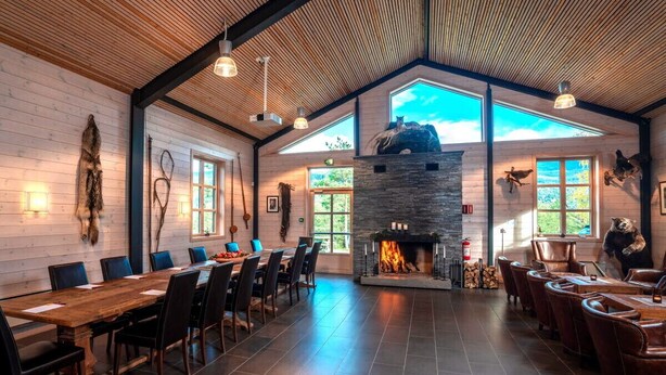 A spacious room with a large wooden table and chairs, a stone fireplace, and large windows allowing natural light. - Thon Hotel Bjørneparken (Flaa)