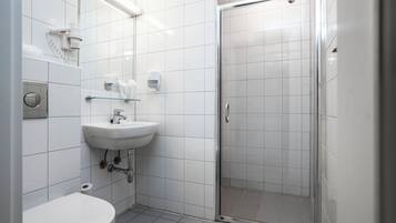 Un baño moderno con lavamanos, inodoro y cabina de ducha de vidrio.