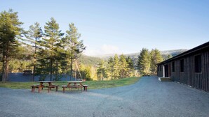 A rustic cabin with a gravel driveway leading to a picnic area with benches. - Thon Hotel Bjørneparken (Flaa)