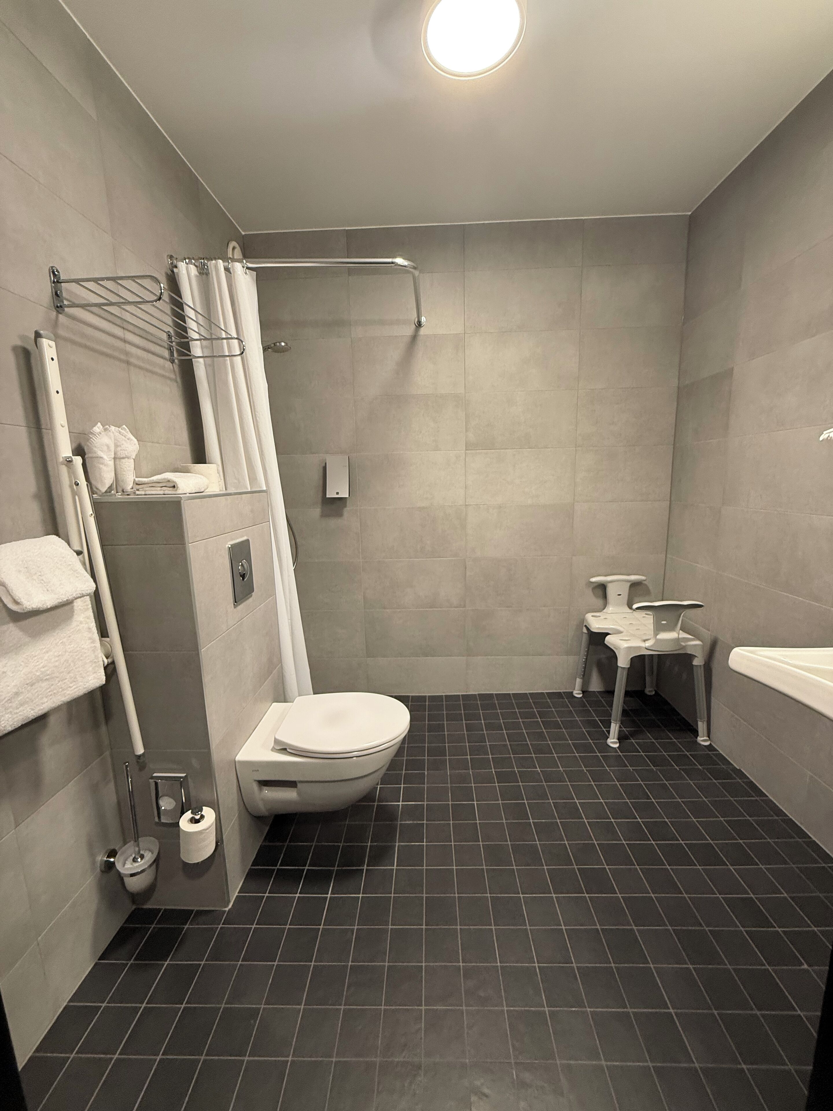 A modern bathroom with a shower, toilet, and a small vanity area.