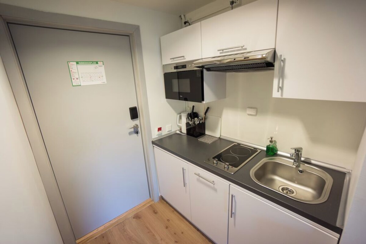 A compact kitchen with a microwave, stove, sink, and cabinets.
