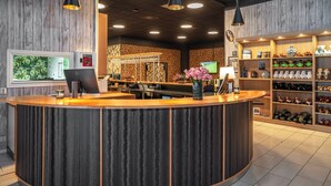 A reception area with a wooden counter, a fish tank, and shelves with stuffed animals. - Thon Hotel Bjørneparken (Flaa)
