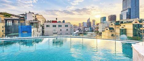 A rooftop pool with a cityscape view, surrounded by buildings of various architectural styles.