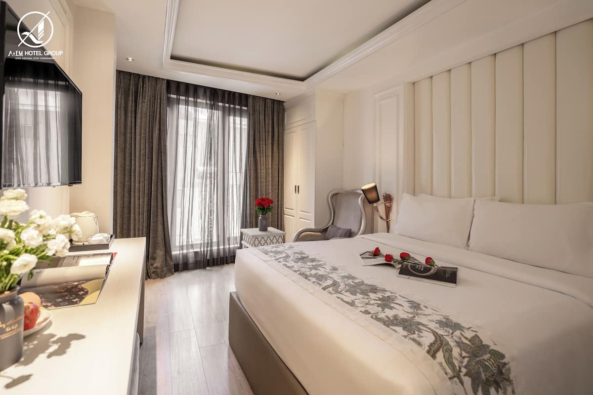Una habitación de hotel con una cama grande, un escritorio con una computadora portátil, una silla y un televisor.