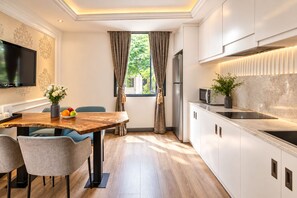 A modern kitchen with a dining area, a flat-screen TV, and a view of greenery outside. - A&EM Saigon Hotel (Ho Chi Minh City)