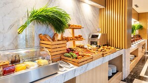 Een buffetgedeelte met diverse soorten eten, een koffieapparaat en een plant.
