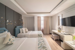 Ein Hotelzimmer mit zwei Betten, einem Schreibtisch, einem Fernseher und einem großen Fenster mit Vorhängen.