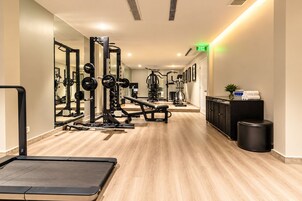 A gym with various exercise equipment, a mirrored wall, and a wooden floor.
