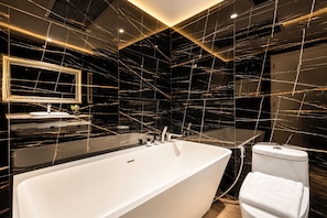 Une salle de bain moderne avec une baignoire sur pieds, des toilettes et un meuble-lavabo avec un miroir.