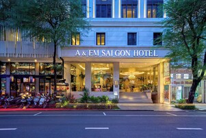 The exterior of A & EM Saigon Hotel with a modern facade, large glass windows, and a well-lit entrance.