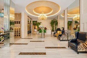 Eine großzügige Lobby mit einer Kronleuchter, einer Sitzecke und einer Rezeption.