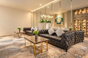 Un salon moderne avec un canapé en cuir, une table basse en marbre et un grand miroir.