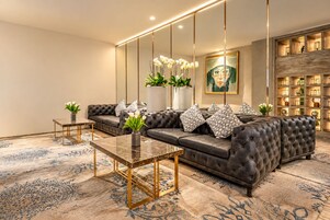 A modern living room with a leather sofa, a marble coffee table, and a large mirror.