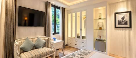 A modern bedroom with a large bed, a sofa, a TV, a wardrobe, and a bathroom with a mirror and shelves.