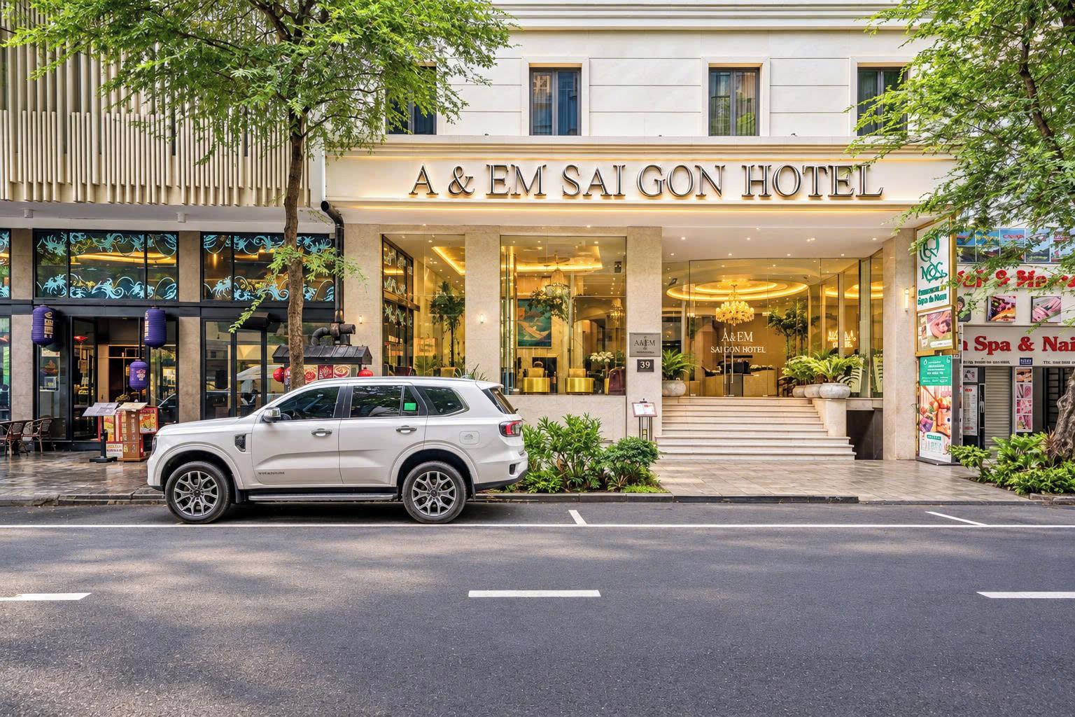 Exterior do Hotel A & EM Saigon, com um carro branco estacionado na frente.