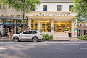 La façade de l’hôtel A & EM Saigon, avec une voiture blanche garée devant.