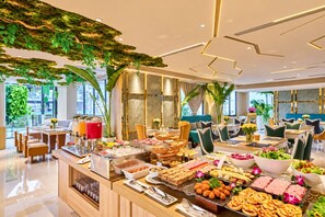 Een restaurantgedeelte in een hotel met een buffetopstelling, zitmogelijkheden en uitzicht op het omliggende landschap.