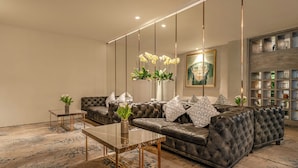 Ein modernes Wohnzimmer mit einer Ledersofa, einem Glastisch und einer dekorativen Vase mit Blumen.