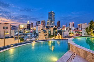 A cityscape with a pool area featuring a curved edge and a clear view of the skyline.