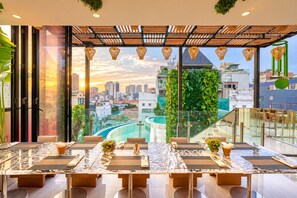 A dining area with a city view, a glass railing, and a wooden ceiling. - A&EM Saigon Hotel (Ho Chi Minh City)