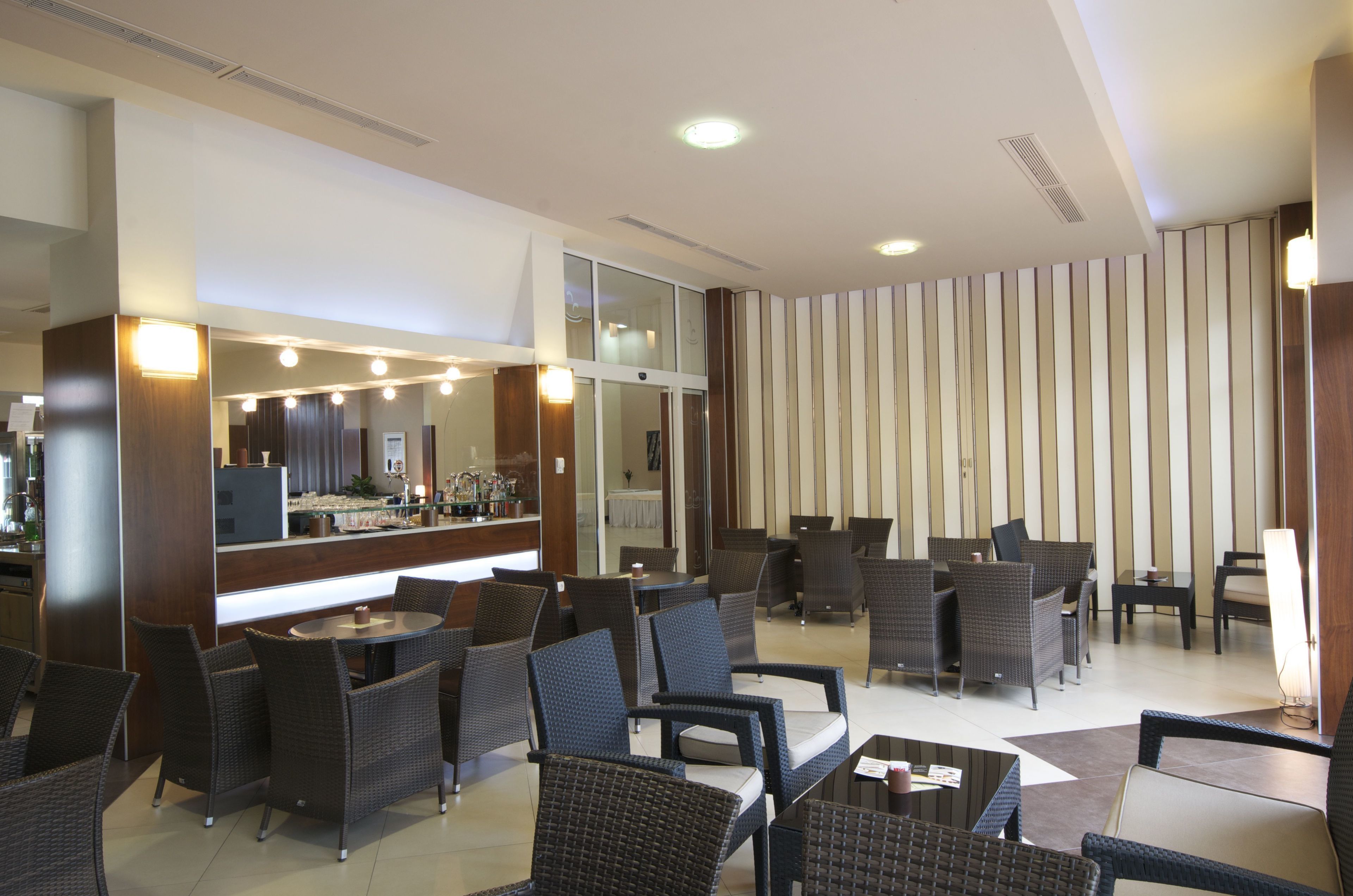 A modern lounge area with wicker furniture, a bar, and a large mirror.