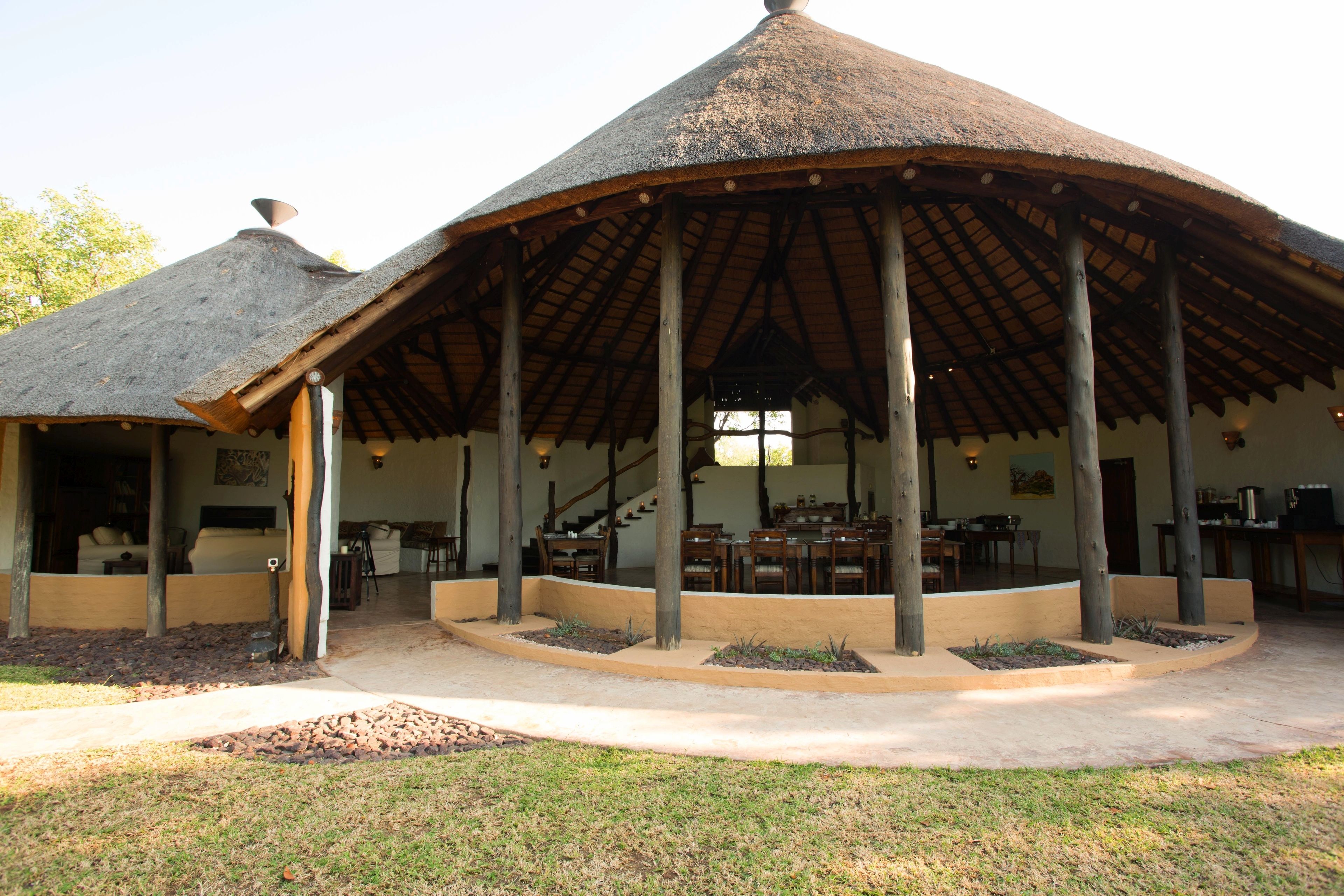 A covered outdoor area with a thatched roof, wooden pillars, and a seating arrangement.