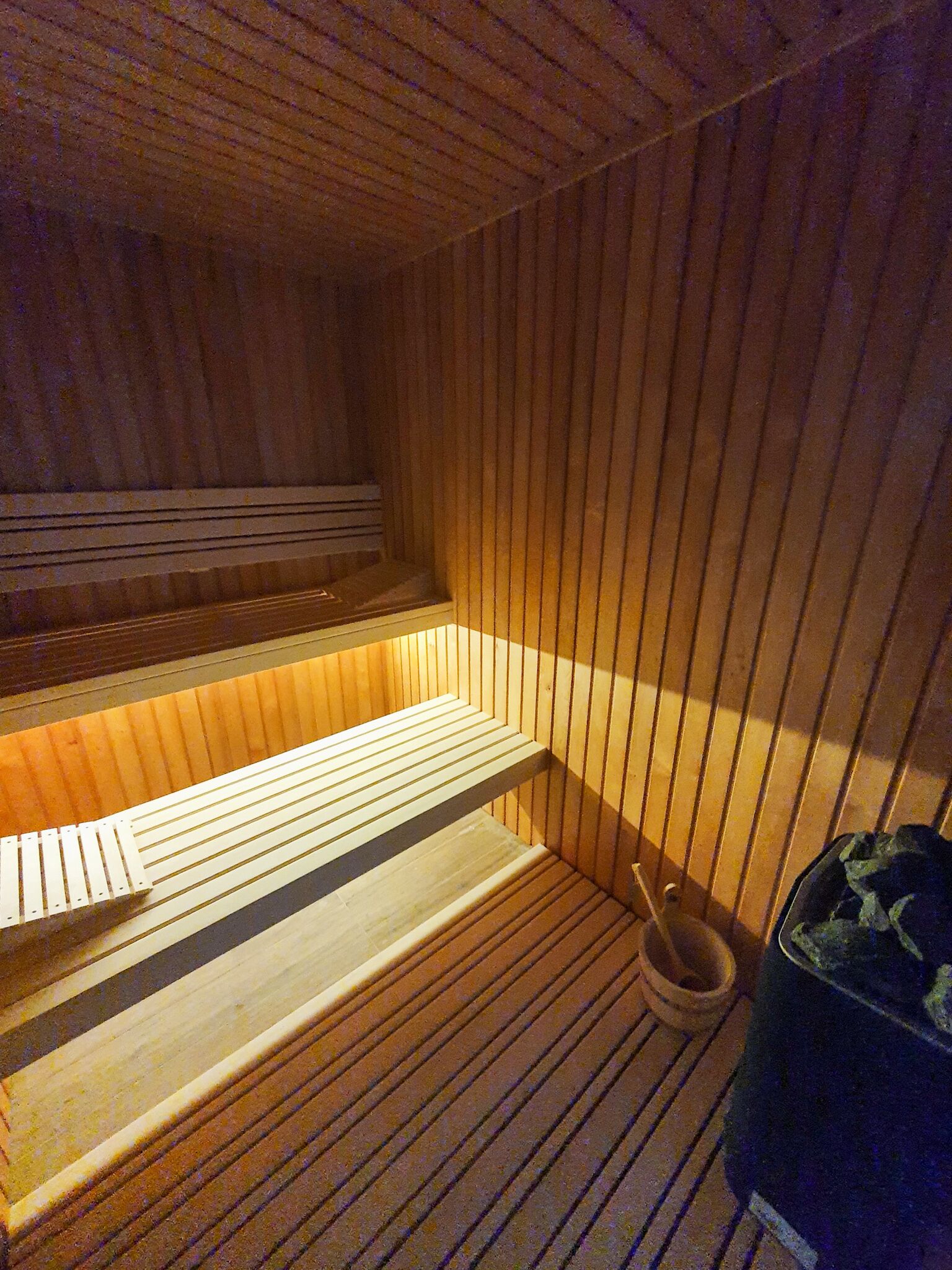 A sauna with wooden benches and a bench with a backrest.